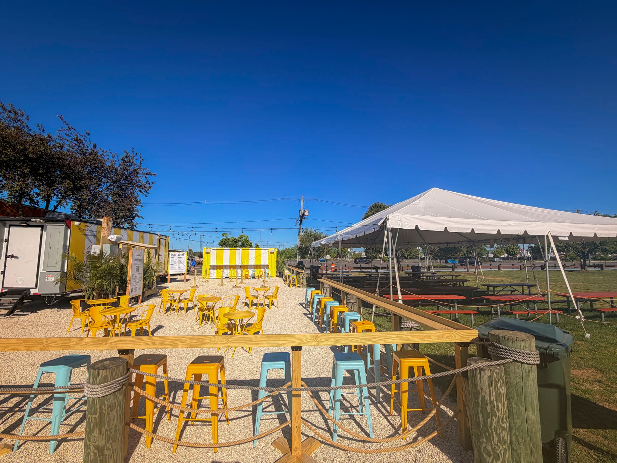 Luca's Beach Kitchen patio with yellow seating, beach tent, and waterfront views